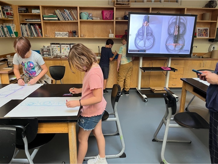 two students kinetic drawing at a table