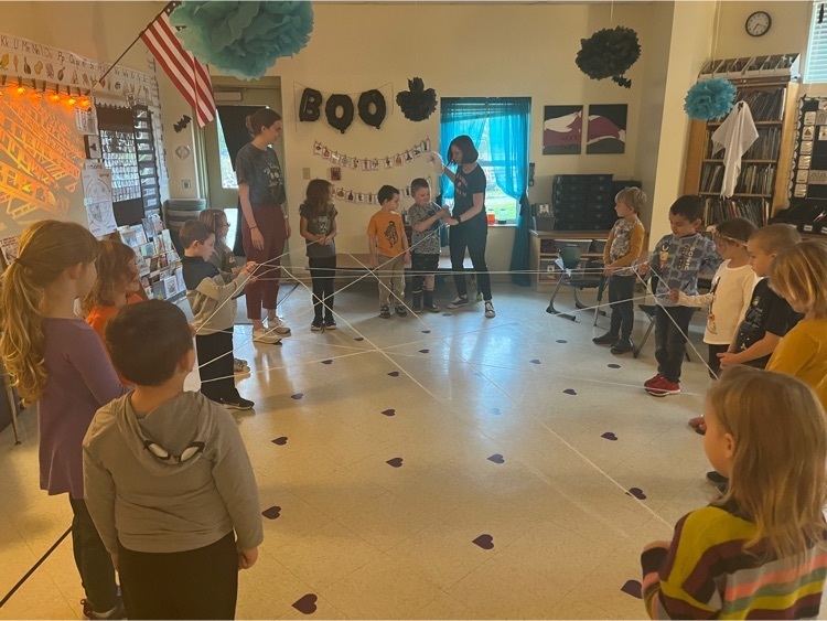 Students standing in a circle holding yarn and creating a spider web