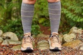 A person's legs with tall socks and hiking sneakers standing on the ground
