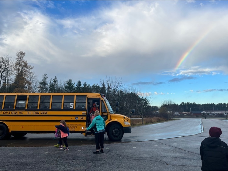 students getting off the bus with a rainbow overhead