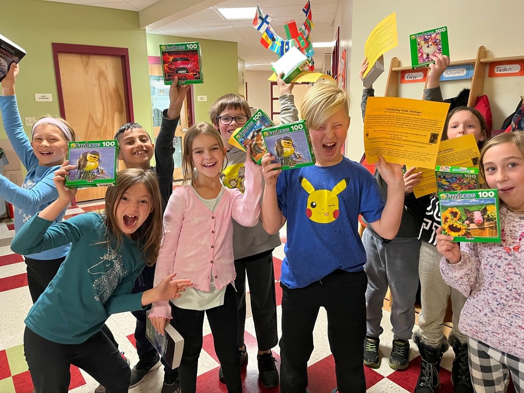 Students excitedly showing off their Thanksgiving challenge sheets and puzzles