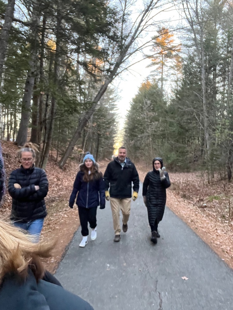 students and staff walking on a tar path in the woods