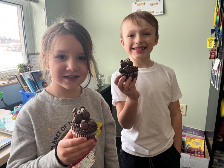 two first graders holding chocolate cupcakes decorated to look like groundhogs 