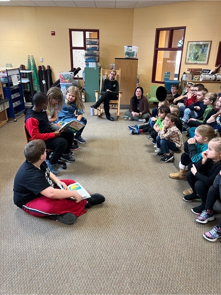 students reading to a younger group of students